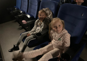 Dziewczynki siedzą na fotelu w kinie.